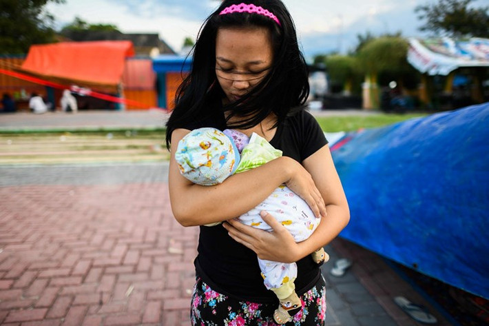 Người phụ nữ còn sống sót sau thảm họa ở Indonesia ôm chặt lấy cậu con trai bé nhỏ 2 tháng tuổi trong vòng tay. Ảnh: AFP.