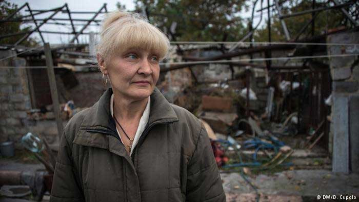 Cô Svetlana Zavadenko đứng trước ngôi nhà của mình ở Spartak. Sau khi được mọi người cứu ra khỏi đống nhà đổ nát do bị trúng đạn pháo, cô đã bị gãy 6 sương sườn và rách một lá phổi. Ảnh DW