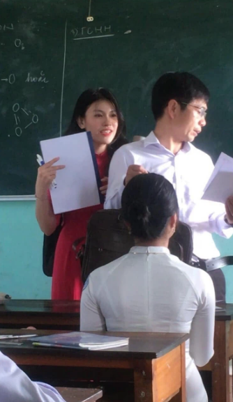 Diện áo dài màu đỏ, cô giáo trẻ có một nụ cười thật tươi cùng mái tóc dài uốn nhẹ cực nữ tính. Dù chỉ là ảnh chụp lén nhưng vẻ đẹp của cô cũng khiến nhiều người "đổ gục".