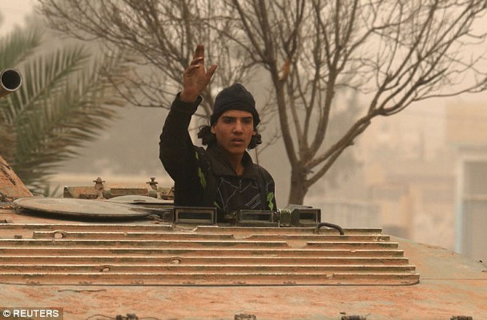 Một chiến binh nổi dậy Syria đứng trong xe bọc thép BMP đang trên con đường ở Dahiyat al-Assad, phía tây thành phố Aleppo. Ảnh Daily Mail