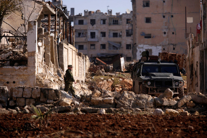 Một lính Nga đang đi về phía xe quân sự ở quận Hanono, Aleppo. Ảnh Sputnik