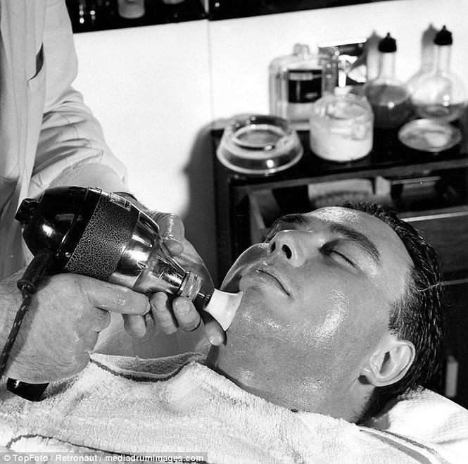 Chuyên gia làm tóc đang massage mặt cho nam khách hàng bằng chiếc máy kỳ lạ.