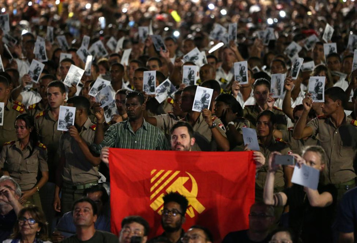 Các học viên giơ cao cờ và di ảnh cố nhà lãnh đạo Fidel Castro tại buổi lễ. Ảnh Reuters