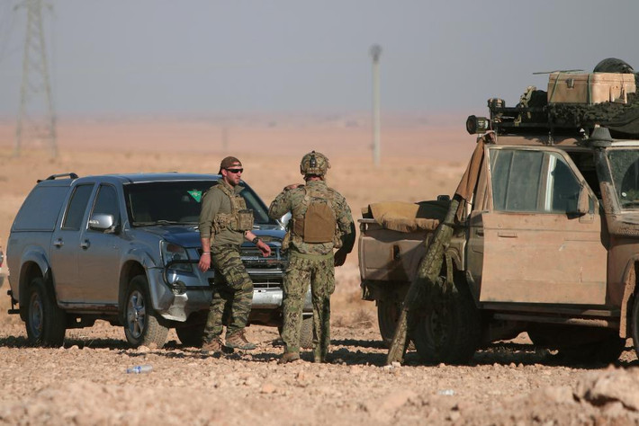 Lính Mỹ đứng gần các xe quân sự ở mạn bắc thành phố Raqqa, Syria. Ảnh Reuters