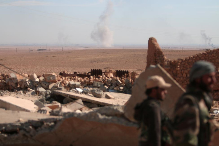 Khói bốc lên ở phía xa xa khi các thành viên SDF lục soát hiện trường đổ nát ở bắc thành phố Raqqa. Ảnh Reuters