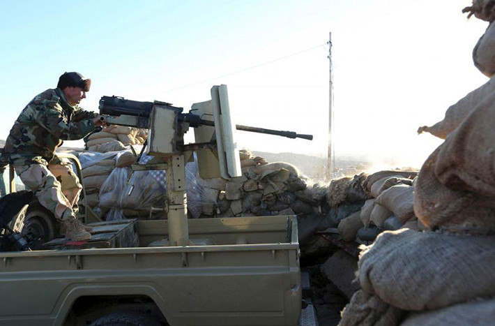 Cảnh một dân quân người Kurd nã đạn về phía IS trong trận đụng độ ở thị trấn Sinjar.