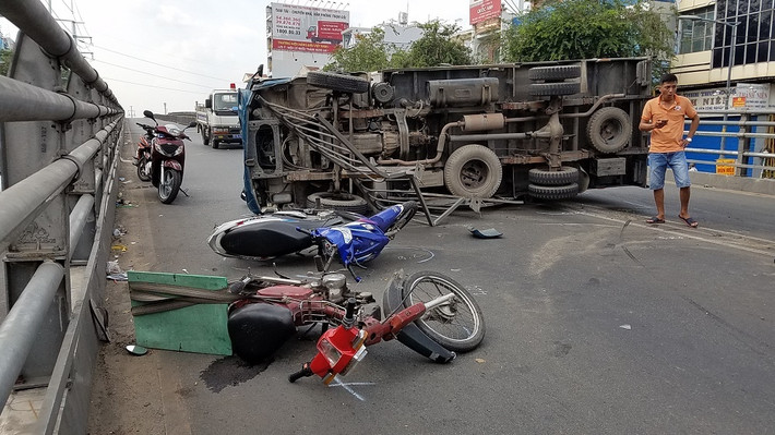 1. Xe tải lật ngang trúng người đi đường: Khoảng 13h ngày 20/1, một chiếc xe tải BKS 51C- 514.88 chạy trên đường Hồng Bàng, hướng từ quận 5 đi quận 6 (TP HCM) với tốc độ khá cao. Khi gần đến giữa cầu vượt Cây Gõ, phương tiện này bất ngờ lao sang trái húc văng hàng loạt dải phân cách bằng thép giữa đường. Không chịu dừng lại chiếc xe tải tiếp tục lao sang phần đường ngược lại rồi lật ngang đường trúng 2 xe máy do một 1 nam và 1 nữ điều khiển chạy ngược hướng. (Ảnh: Thảo Nguyện/Vietnamnet)