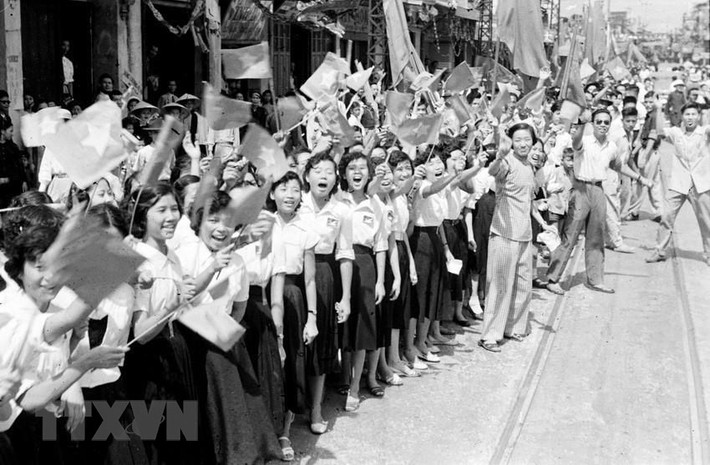 Học sinh, sinh viên cùng người dân vẫy cờ chào đón đoàn quân chiến thắng về giải phóng Thủ đô, sáng 10/10/1954. Nguồn: Tư liệu TTXVN.