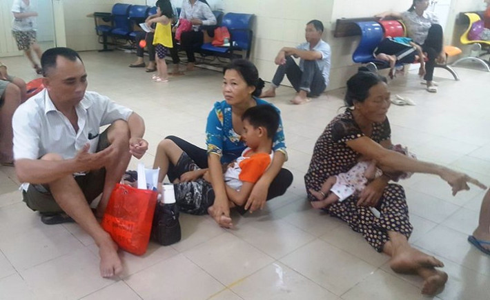 Bố mẹ cũng vạ vật ngồi bệt xuống sàn nhà cho đỡ nóng chờ đến lượt con được khám bệnh.