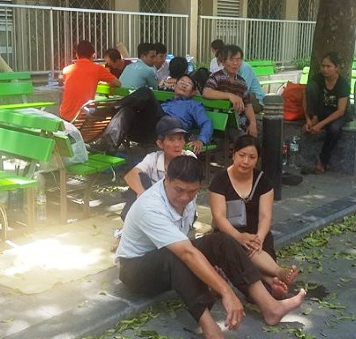 Người nhà bệnh nhân chọn gốc cây làm chỗ nghỉ ngơi.