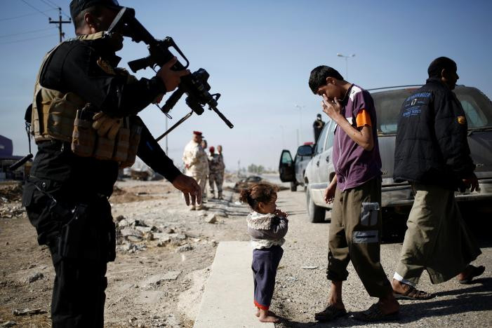 Bé gái đứng cùng người thân ở trạm kiểm soát của Lực lượng đặc nhiệm Iraq ở Kokjali. Ảnh Reuters