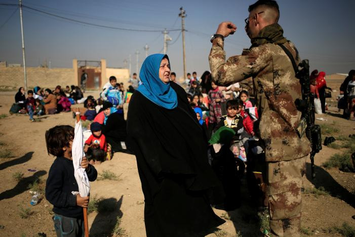 Người binh sỹ Iraq đang cố gắng đảm bảo với người phụ nữ rằng chồng cô sẽ đi cùng các thành viên khác trong gia đình rời đi sau khi anh ta vượt qua vòng tra soát của quân đội. Ảnh Reuters