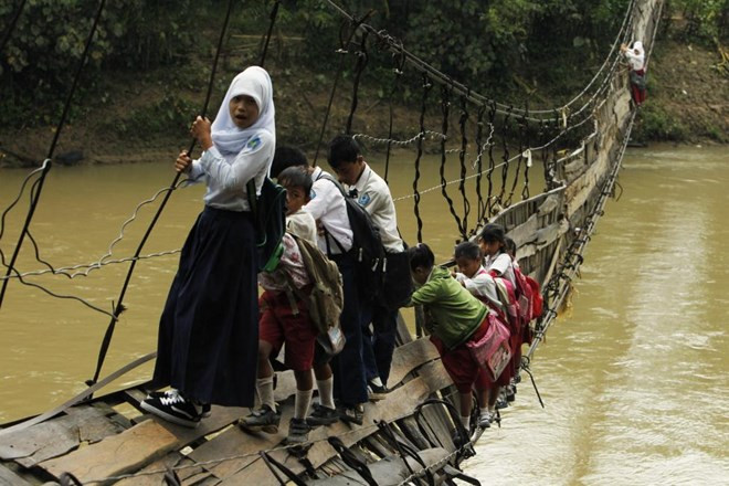Nhóm em học sinh này đang phải đu bám vào cây cầu dây chồng chềnh để băng qua sông đến trường đi học tại làng Sanghiang Tanjung, Indonesia.