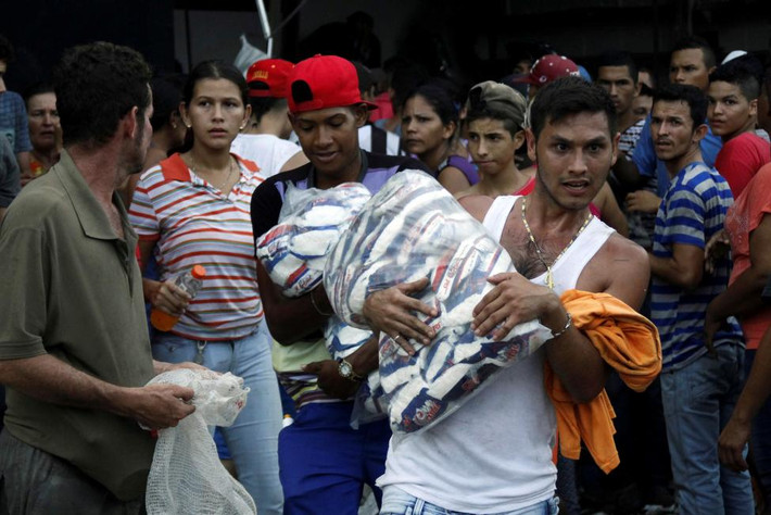 Dân khuân hàng hóa trong một siêu thị ở La Fria. Ảnh Reuters