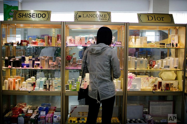 Người phụ nữ đứng trước kệ hàng mỹ phẩm và nước hoa nhập khẩu. (Ảnh: AP)
