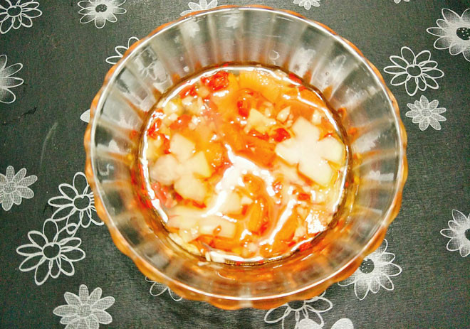 Bước 9: Pha nước chấm, bạn cho đường vào bát, thêm nước lọc, giấm, nước mắm và khuấy đều cho đường tan hết, nếm thử xem độ mặn ngọt, chua của nước mắm như ý là được. Sau cùng thêm ớt băm, tỏi băm cùng với đu đủ, cà rốt tỉa hoa vào trộn đều, chúng ta được bát nước chấm bánh rán mặn.