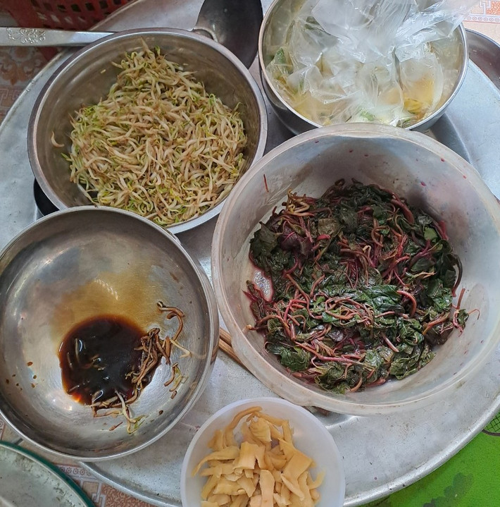 Chồng bà Nở mất cách đây nhiều năm. Lúc còn sống, ông sửa xe đạp dạo ở vườn hoa, bà thì dậy từ 3h đêm đi lấy rau ở chợ Lũng rồi vào các chợ trong thành phố bán. Hai vợ chồng rau cháo nuôi đàn con tâm thần.