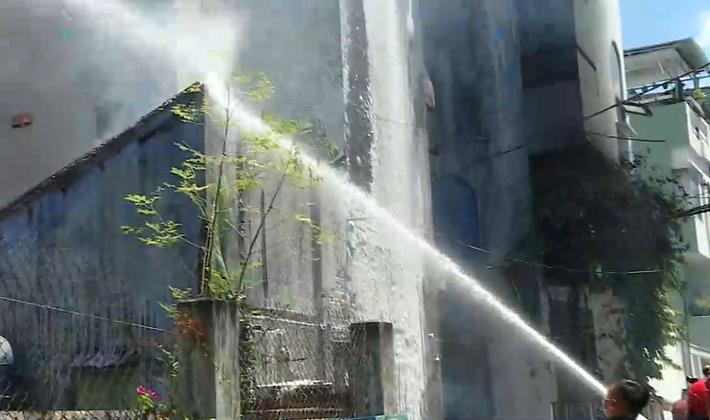 Lửa tiếp tục cháy lan sang một ngôi nhà bỏ hoang, cột khói đen bốc cao, bao trùm cả khu vực khiến nhiều người hoảng loạn.