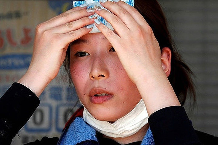 Một người phụ nữ phải dùng khăn lạnh để chườm lên trán vì thời tiết oi nóng khó chịu. Ảnh: Reuters