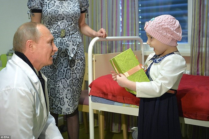 Tổng thống Putin tặng quà và hỏi thăm một bé gái tại Trung tâm Dmitry Rogachev năm 2016. Đây là trung tâm nghiên cứu công nghệ cao và điều trị cho những trẻ em mắc các bệnh về máu, ung thư và hệ miễn dịch. Ảnh: EPA