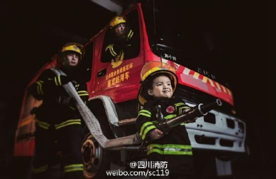 Người lính cứu hỏa nhí này nhận được rất nhiều sự giúp đỡ của những anh chàng cứu hỏa thật sự, nhất là trong những công việc nặng nhọc như cầm vòi phun nước. Ảnh: Weibo.
