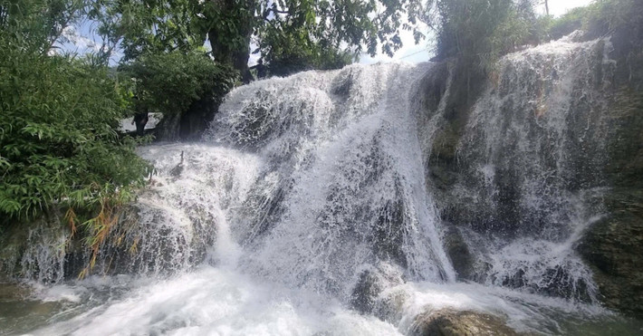 Ẩn mình giữa núi rừng đại ngàn của xứ Mường, thác Trăng như một dải lụa bạc mềm mại buông xuống từ độ cao hàng chục mét. Nước thác đổ xuống tung bọt trắng xóa, âm thanh rì rào vang vọng giữa không gian xanh mát, tạo nên một bản hòa ca của thiên nhiên khiến ai đến đây cũng phải sững sờ. Ảnh baohoabinh