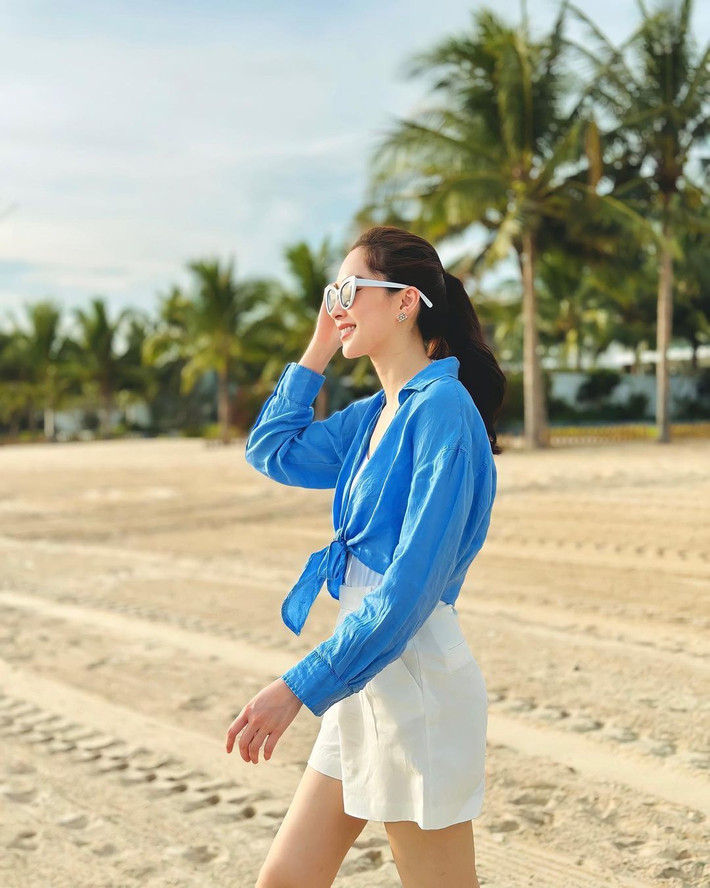 Đôi khi thay đổi phong cách, Đặng Thu Thảo thả dáng trên bãi biển với trang phục phối hai gam màu trắng - xanh mát mắt. Bà mẹ hai con diện quần shorts tôn chân thon, kết hợp sơ mi thắt nơ ngang eo kín đáo.