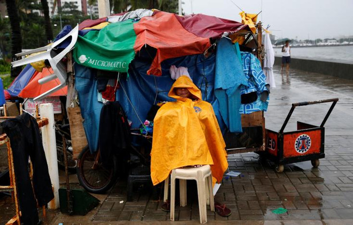 Người đàn ông ngồi trú mưa ở Manila hôm 16/10.