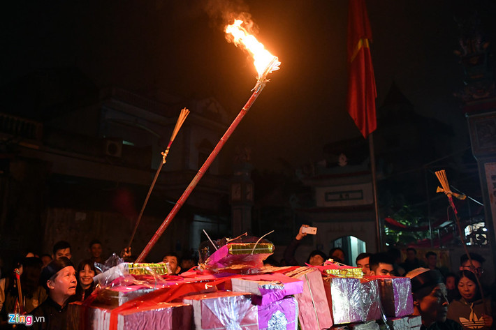 Một bô lão trong làng xin lửa từ trên điện thờ. Sau khi mang vàng hương đổ ra giữa sân, cụ châm lửa Thánh từ cây sào lớn để hoá.