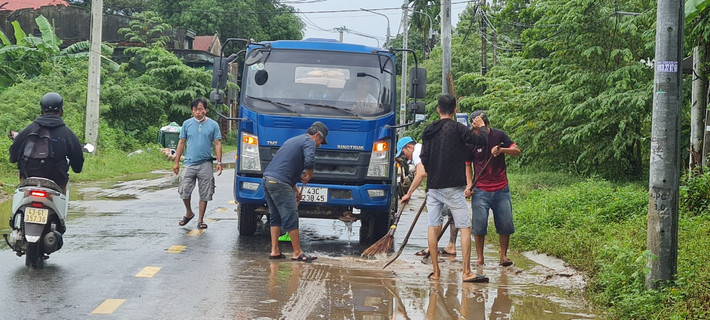 Hàng chục người và phương tiện cấp tập dọn bùn tràn ra đường sau mưa lớn.