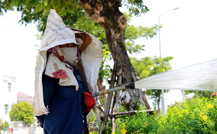 Để hạn chế nắng nóng, chị Nguyễn Thị Lan (công nhân Công ty Môi trường đô thị) phải xé bao xi măng che nắng.