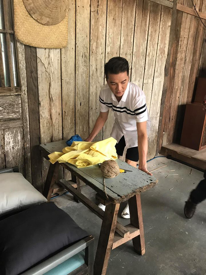 Trong hình ảnh, Mr Đàm mặc áo sơ mi ngắn tay kết hợp với quần short tối màu "cơ động" bê bàn ghế, đồ vật bố trí khung cảnh trước khi buổi họp báo diễn ra.