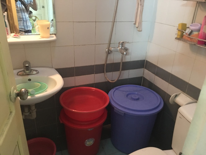 Xô tích trữ nước chật kín nhà tắm. "Do thiếu nước sinh hoạt nên gia đình phải lấy nước rửa rau để tráng bát hay dùng nước tắm của trẻ để giặt quần áo rồi mới dội bồn cầu nhà vệ sinh" - một người phụ nữ sinh sống tòa B15 cho hay.