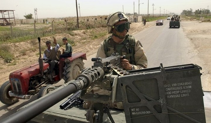 Binh sĩ Mỹ bên súng máy trên xe humvee hộ tống một nhóm quân nhân thuộc không quân Mỹ khi đi trên đường.