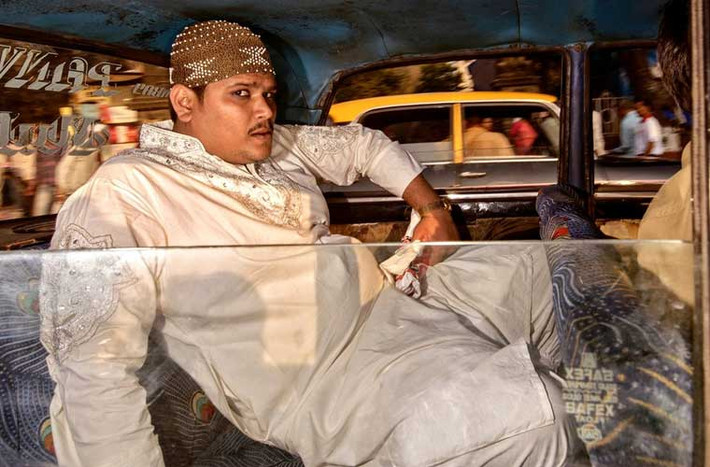Nam hành khách ngồi thoải mái ở ghế sau taxi hướng mắt nhìn theo ống kính máy chụp.