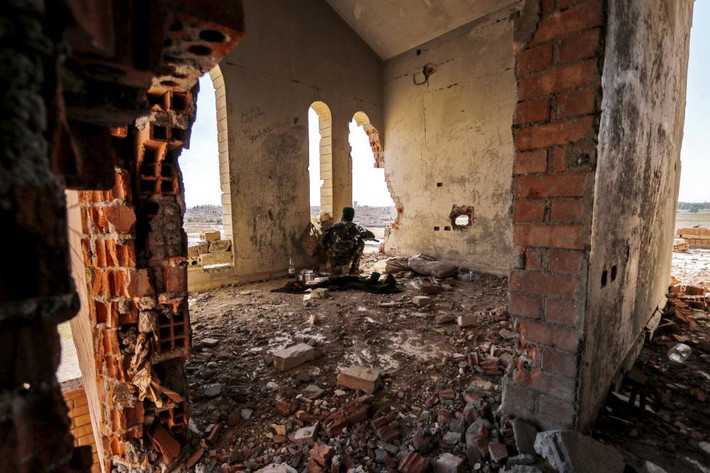 Một dân quân YPG đứng nấp bên trong ngôi nhà đổ nát ở khu al-Vilat al-Homor khi theo dõi các động tĩnh của IS.