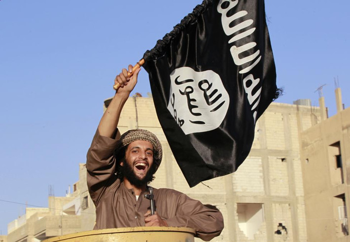 Nhóm phiến quân Hồi giáo (IS) đang nổi lên là một lực lượng đáng gờm trong cuộc chiến Syria. Trong ảnh, một chiến binh IS vẫy cờ đen khi diễu phố dọc các con đường ở Aleppo ngày 30/6/2014.