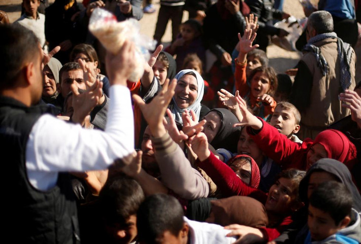 Người tị nạn Iraq tranh nhau nhận đồ cứu trợ. Ảnh Reuters