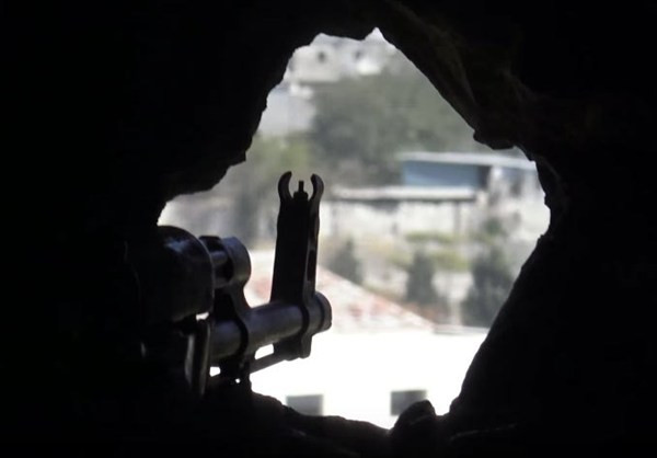 Họng súng của một binh sỹ Syria ngắm qua lỗ châu mai ở công sự.
