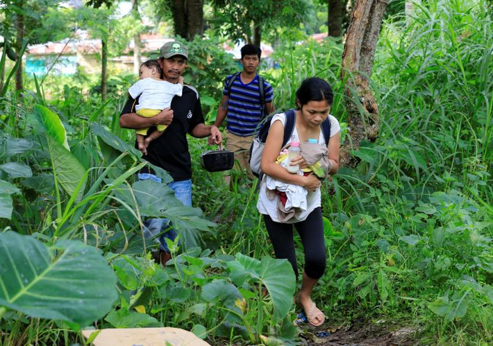 Người dân bế con nhỏ, băng qua rừng để tới trung tâm sơ tán nhằm tránh cuộc xung đột giữa quân đội và nhóm Maute.