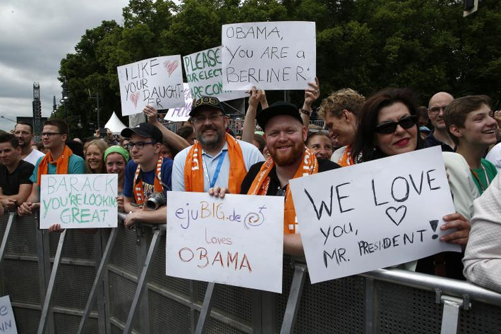 Mọi người mang theo những tấm biển chào đón sự trở lại Berlin của ông Obama.