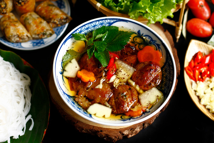 Nếu phở là nét thanh tao, thì bún chả lại mang dáng vẻ dung dị, gần gũi như chính con người Hà Nội. Từ xa, mùi thơm của thịt nướng trên bếp than đã khiến lòng người xốn xang. Chả miếng vàng ruộm, chả viên mềm thơm, nhúng vào bát nước chấm chua ngọt, ăn kèm với rau sống tươi rói, tất cả hòa quyện để tạo nên một bản giao hưởng của vị giác. Món ăn mà cựu Tổng thống Obama từng dành lời khen khi ghé thăm Hà Nội. Ảnh Internet