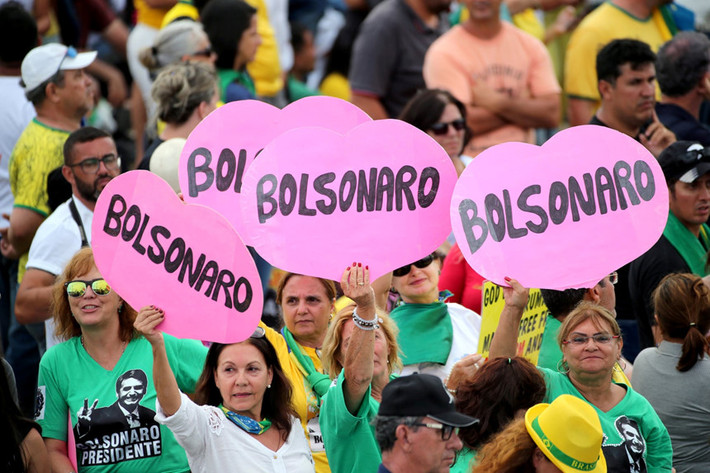 Những người ủng hộ Tổng thống Bolsonaro bên ngoài Planalto. An ninh cho buổi lễ được thắt chặt chưa từng thấy. Bolsonaro đang nhận được làn sóng ủng hộ nhiệt tình từ những người Brazil bảo thủ với lời hứa đưa đất nước trở về quá khứ truyền thống. Trong bài phát biểu tại dinh tổng thống, ông nói rằng người Brazil giờ đây có thể "mơ ước cuộc sống tốt đẹp hơn" và khẳng định sẽ "thiết lập lại trật tự ở đất nước". Ảnh: Reuters.