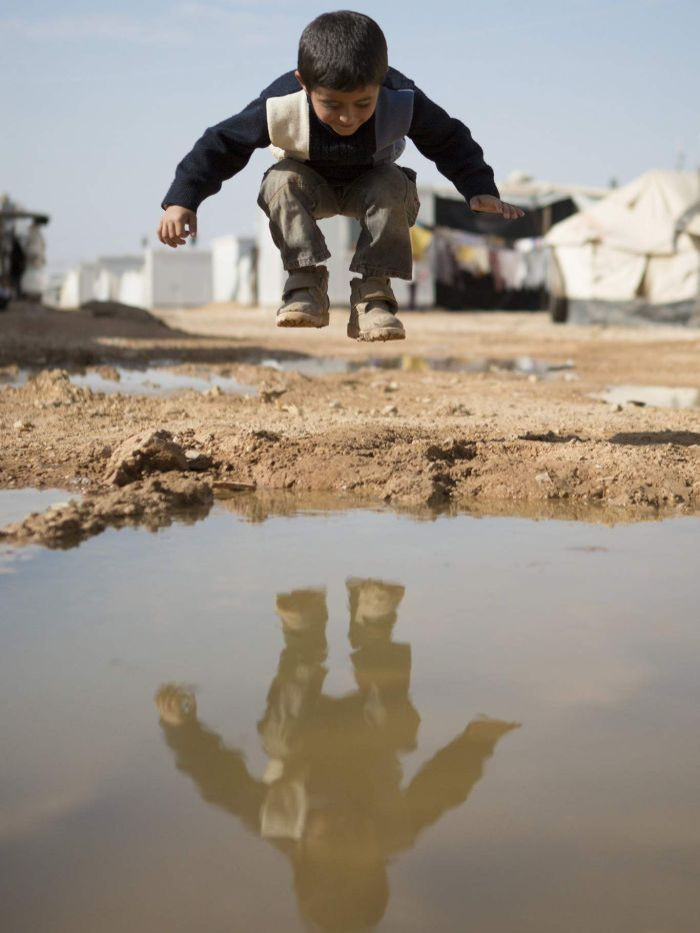 Bé trai tị nạn người Syria đang tự chơi một mình quanh một vũng nước ở trại tị nạn Zaatari, Jordan.