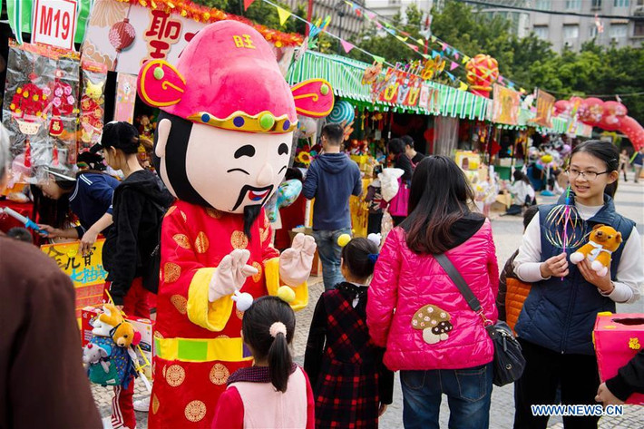 Nhân viên cửa hàng bán đồ trang trí tại Macau, Trung Quốc hóa thân thành thần tài chào mời khách mua hàng. Hàng trăm triệu người dân Trung Quốc đã rời khỏi các thành phố lớn, về quê ăn Tết âm lịch. Trong ngày đầu năm mới âm lịch, người Trung Quốc sẽ mặc trang phục màu đỏ, biểu trưng cho may mắn và thịnh vượng, tới thăm họ hàng, người thân. Ảnh: China News.
