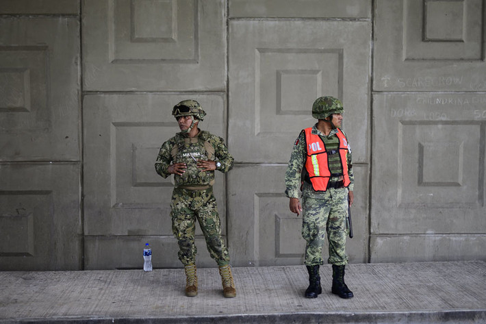Lính thủy quân Lục chiến Mexico cùng quân cảnh của quân đội nước này đứng canh chừng những người nhập cư không có giấy tờ bên ngoài Tapachula, Chiapas, Mexico. Nguồn ảnh: Theatlantic.