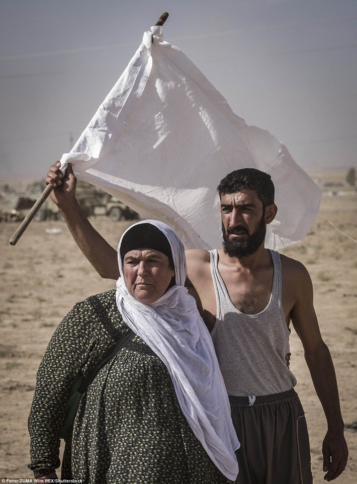 Người đàn ông giơ cao cờ trắng để báo hiệu cho các thành viên lực lượng vũ trang Peshmerga ngừng bắn để họ có thể vượt qua khu vực này để tới nơi an toàn.