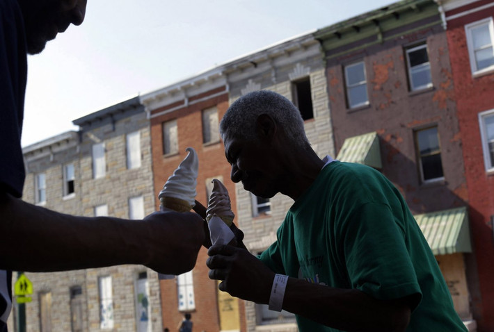 Theo thống kê, mỗi năm có tới 30.000 người dân ở Baltimore trở thành những người vô gia cư. Trong ảnh, hai người vô gia cư đang ăn kem ốc trên con đường dọc dãy phố bỏ hoang.