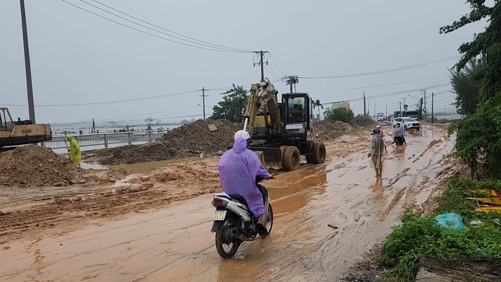 Xe cộ lưu thông từ hai hướng qua đoạn đường này phải vật lộn với mặt đường trơn trượt, sình lầy.