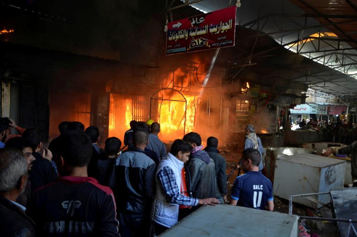 Các gian hàng bùng cháy sau khi hàng loạt các quả súng cối rơi vào khu chợ ở thành phố Mosul. Ảnh Reuters